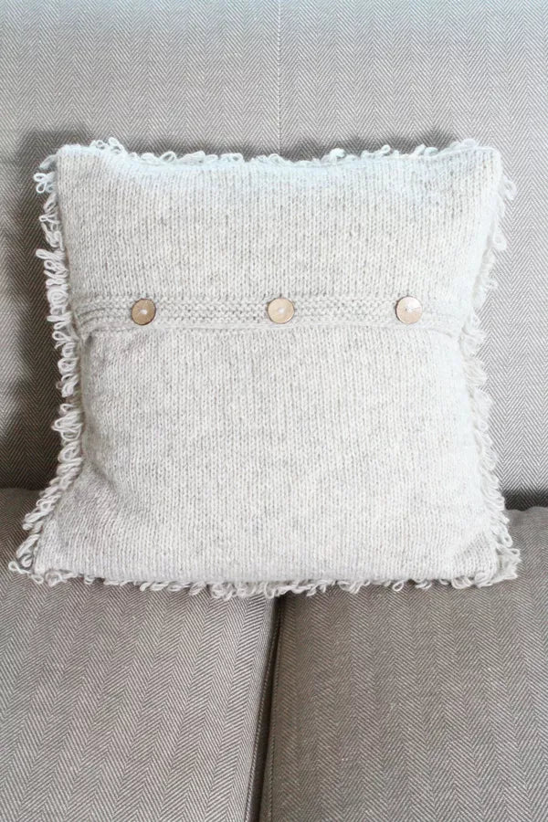 Textured pillow with button details on a gray sofa