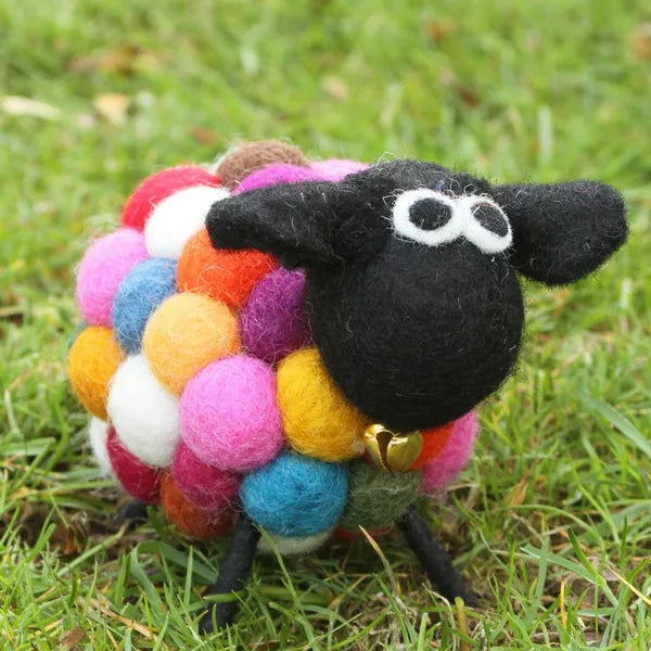 Colorful sheep toy with a black face on grass