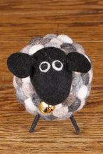 Felted sheep figurine with a bell on a wooden surface