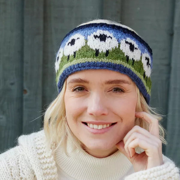 Woman wearing a knitted hat with sheep pattern against a wooden background