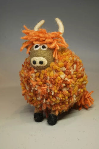 Plush toy cow with orange and brown fur on a gray background