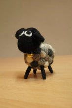 Small felted sheep figurine with a black face and multicolored wool on a wooden surface.