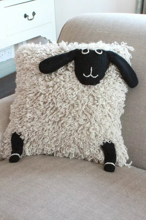 Decorative pillow with a sheep design on a gray couch