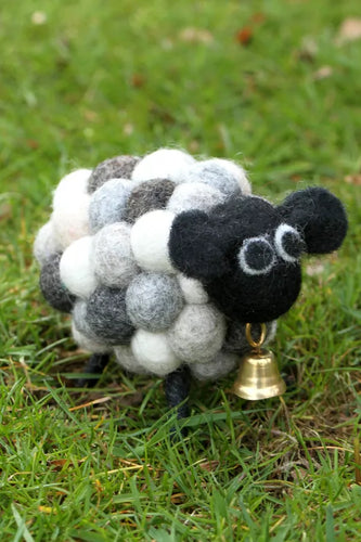 Sheep-shaped toy with a bell on grass