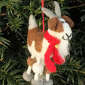 Felted goat ornament with a red scarf hanging on a Christmas tree.