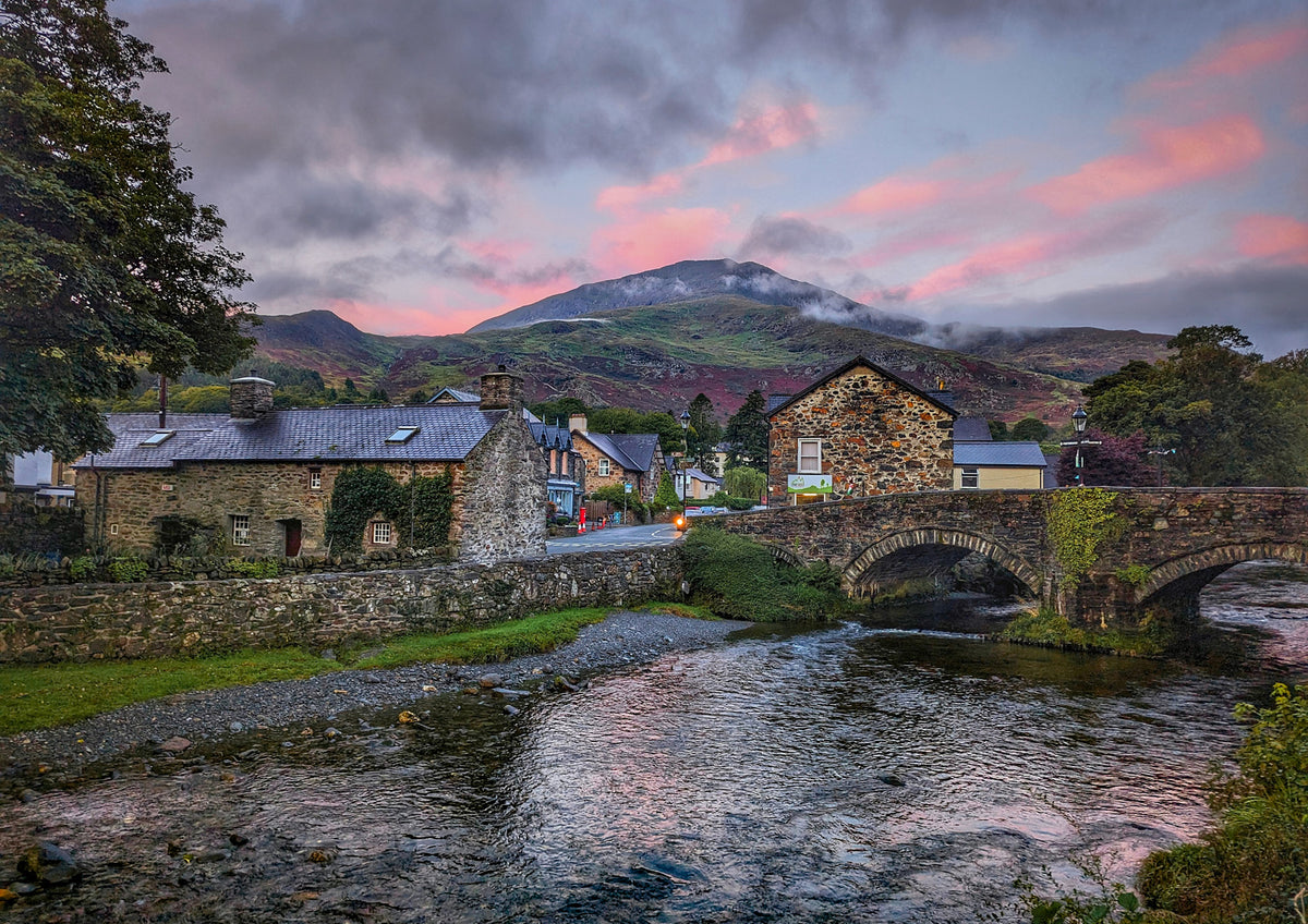 Beddgelert village, the old bridge and the River Glaslyn under a pink evening sky