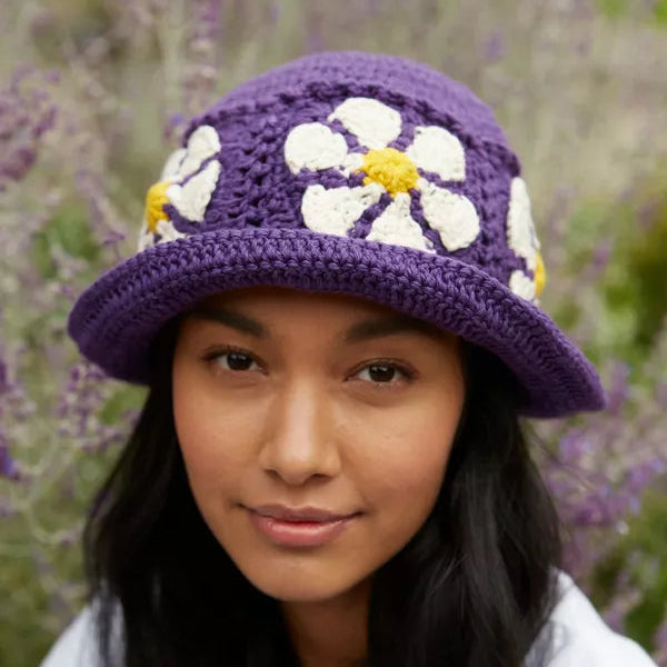 Woman wearing a purple crocheted hat with white flowers in a lavender field